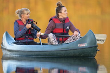 Dos participantes del safari de castores en una canoa listos para tomar fotos de los castores en un safari de castores en Suecia con Nordic Discovery.