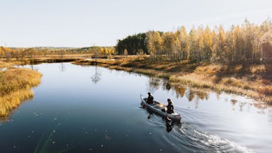 Een stel geniet van de rustige en ongerepte natuur tijdens het kanoën op spiegelglad water.