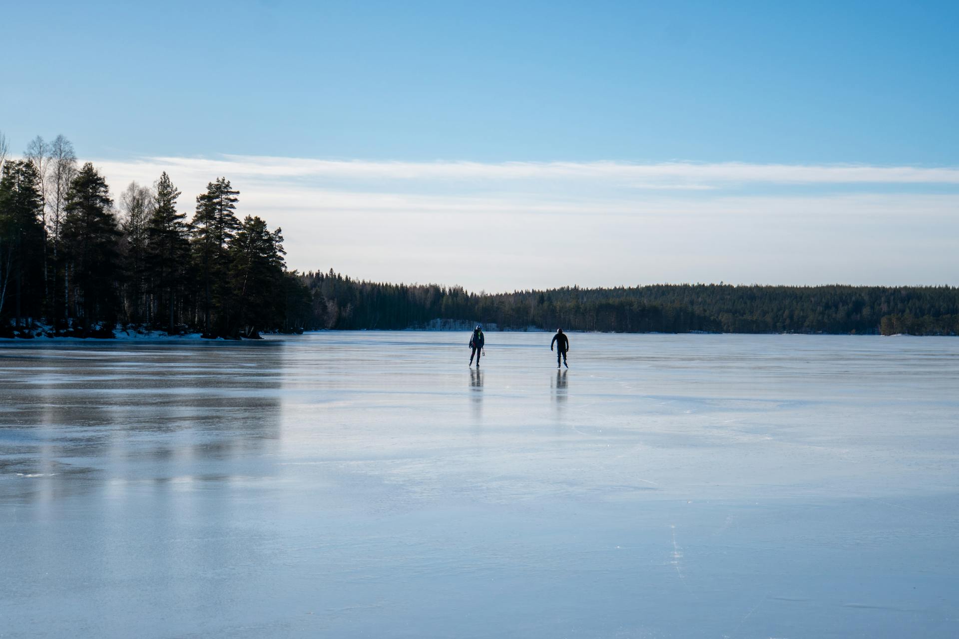 A ice skating duo in the distance enjoying the clar skies and smooth ice during a guided ice skating tour.