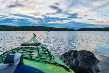 Un kayak sulla riva di un lago con una pietra in primo piano.