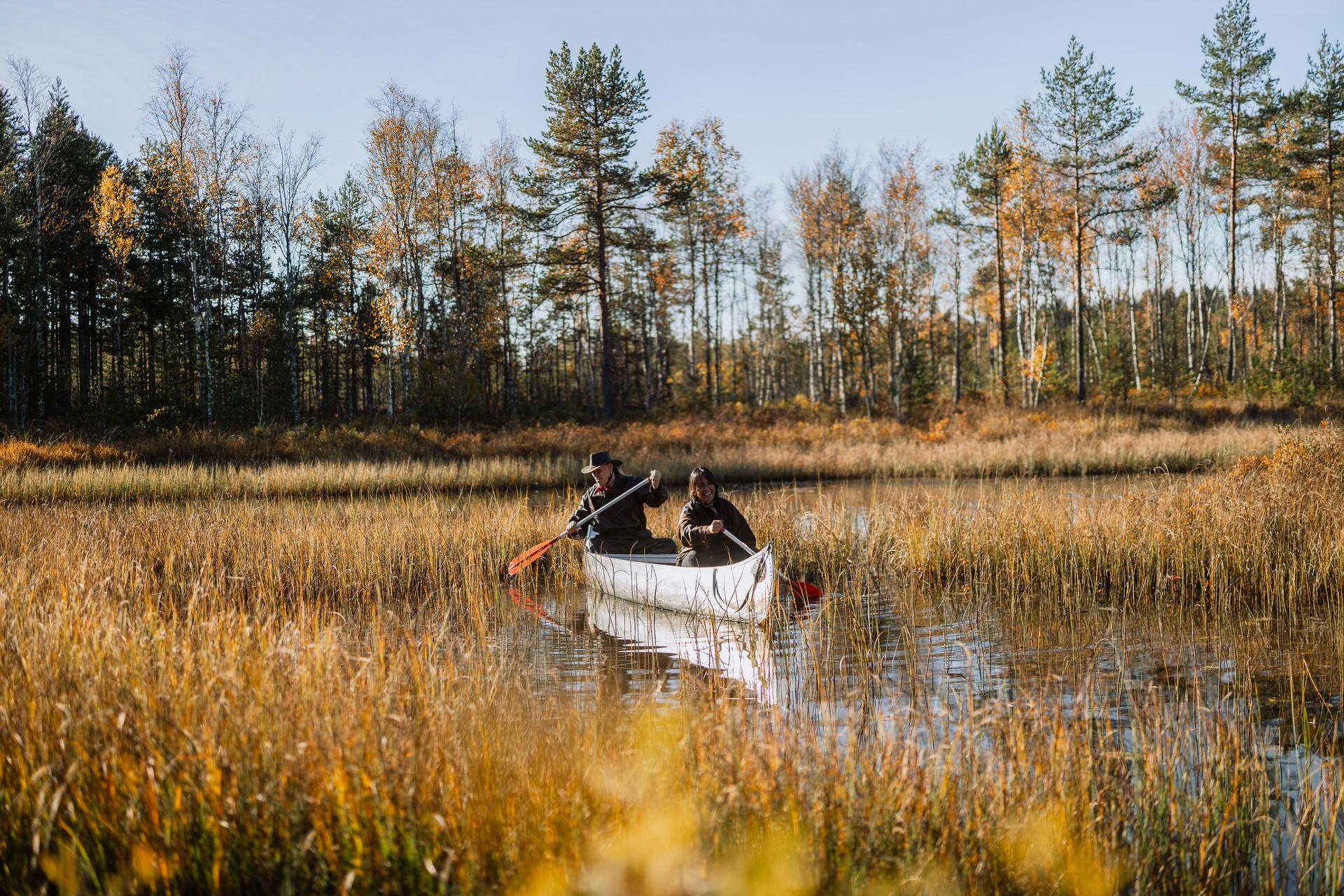 Deux aventuriers heureux explorent la nature suédoise en canoë sur une rivière calme.