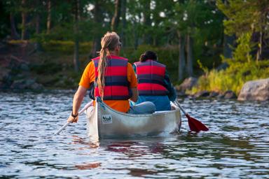 Een kano met twee mensen peddelt in het rustige water van het natuurreservaat Malingsbo-Kloten.