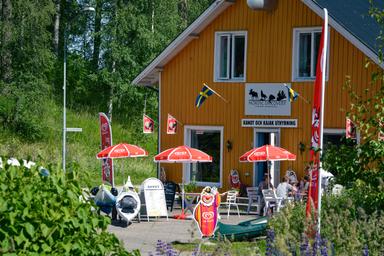 Das Abenteuerzentrum im Sommer, mit Kanus, Kajaks und Personen, die Anweisungen erhalten.