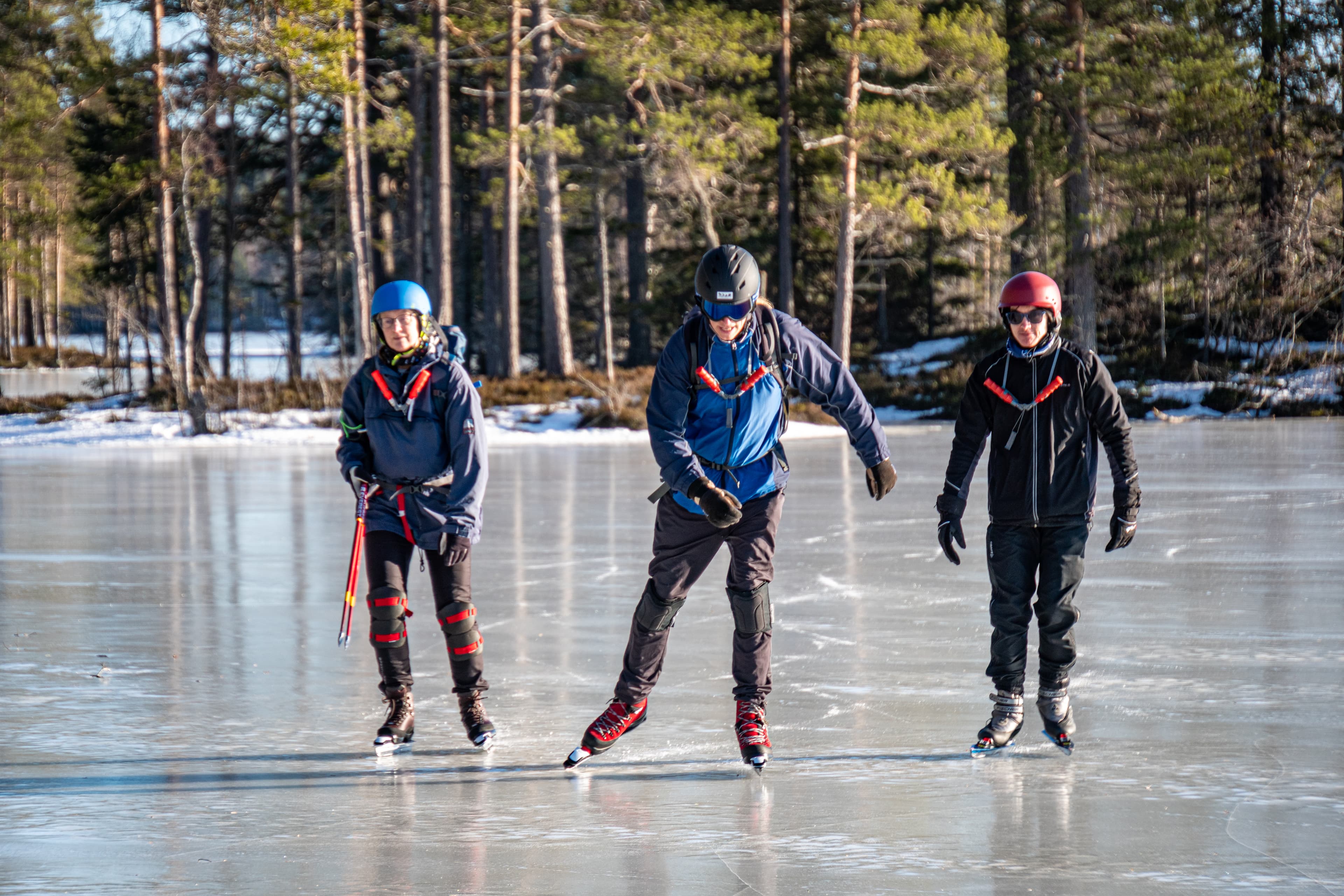 Three ice skaters enjoying a tour on a frozen lake in the Swedish wilderness with Nordic Discovery.