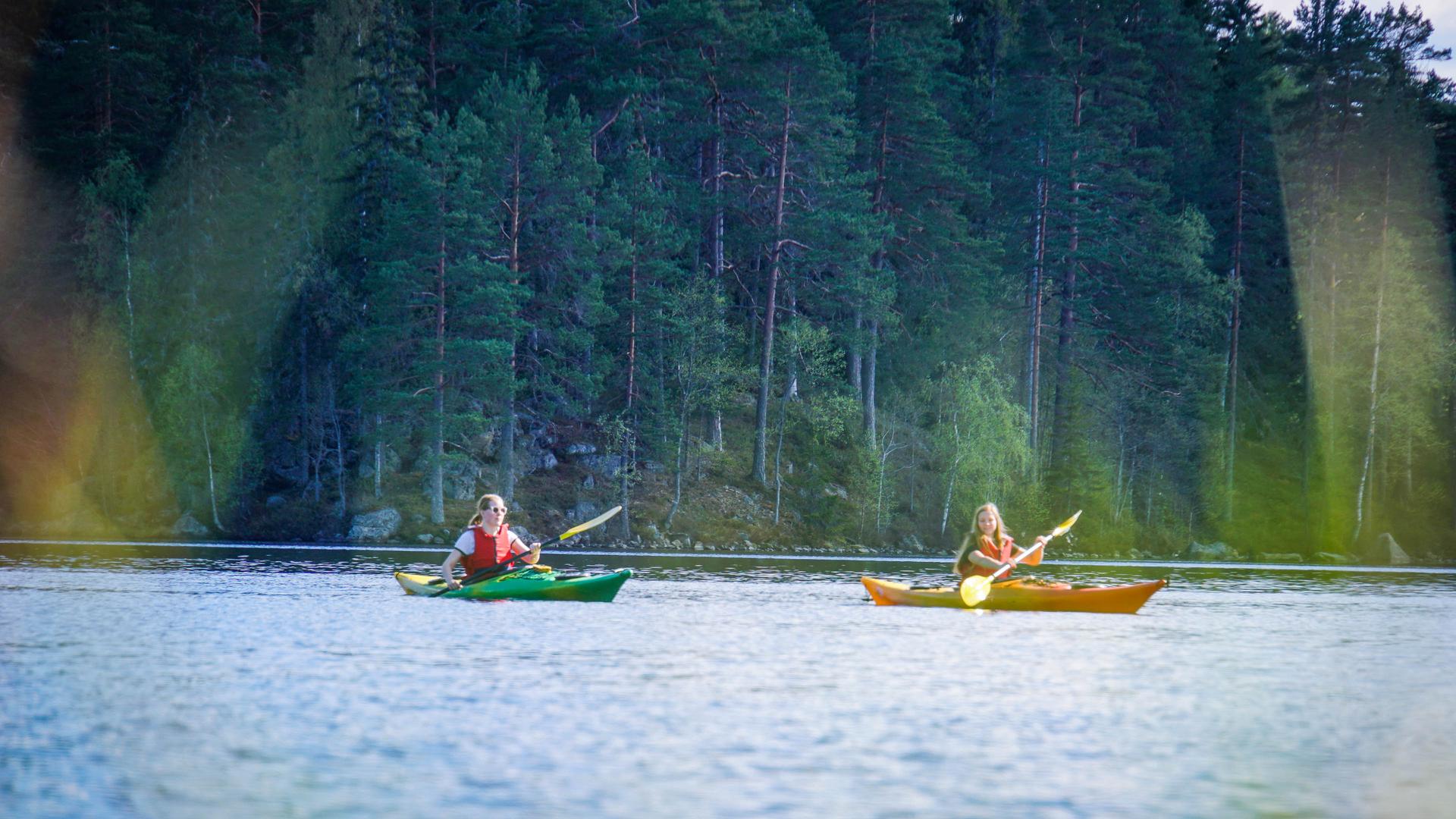 Deux filles heureuses lors d'une excursion en kayak avec Nordic Discovery dans le magnifique paysage suédois.