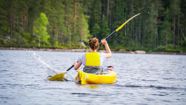 A girl kayaking so the water splashes around her.