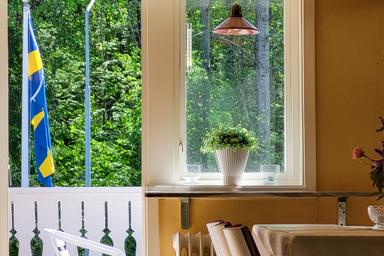 Blick aus dem Küchenfenster mit der schwedischen Flagge und der Wildnis draußen.