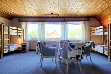 Das Wolfzimmer im Wilderness Lodge in Schweden mit vier Stühlen, einem Tisch und großen Fenstern.