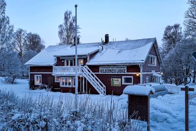 Upplev den förtrollande skönheten i en traditionell svensk Wilderness Lodge på vintern. Fördjupa dig i ett snöigt vinterlandskap omgivet av pittoreska landskap och mysiga boenden.