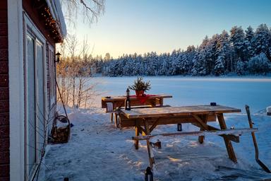 The sauna at River Lodge is in front of the frozen lake on a sunny winter day.