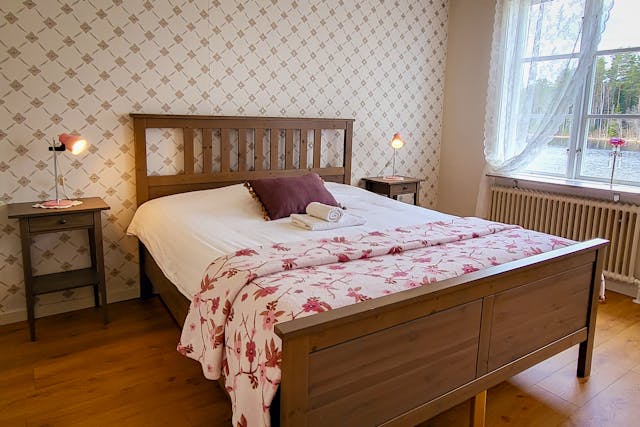Het kanoïst appartement bij River Lodge met een vers opgemaakt bed. De kamer is gezellig en heeft uitzicht op het meer en het bos.