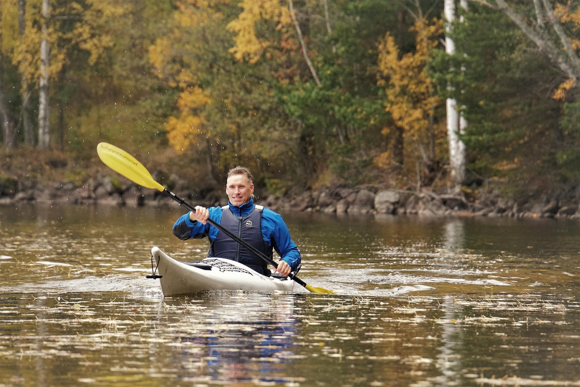 Un homme fait du kayak, envoyant des gouttelettes d'eau voler de la pagaie, dans la réserve naturelle de Malingsbo-Kloten en Suède.